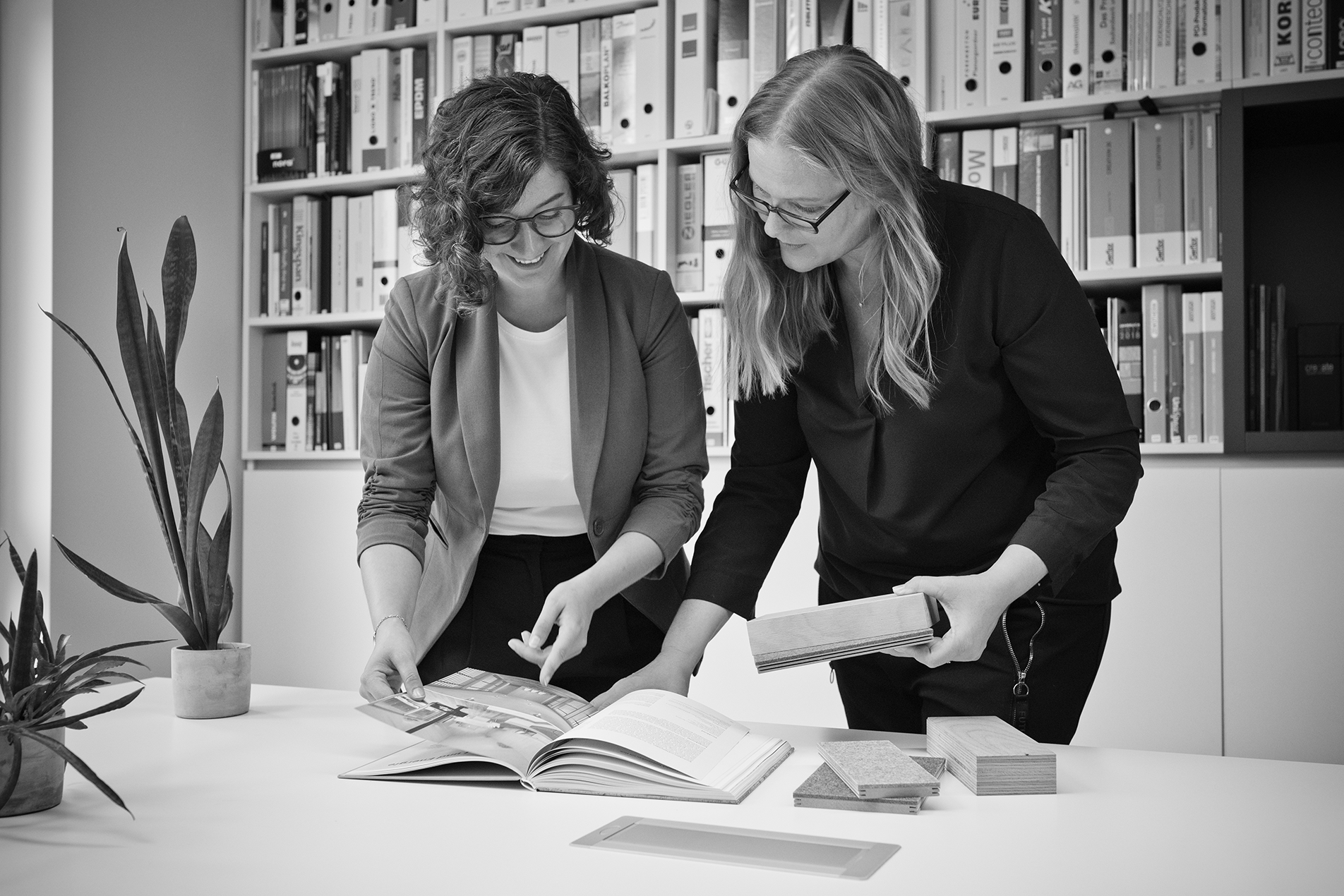 Mitarbeitende im Büro von Haid Architekten | Ingenieure beim Abgleich von Materialmustern mit dem Foto in einem Bildband